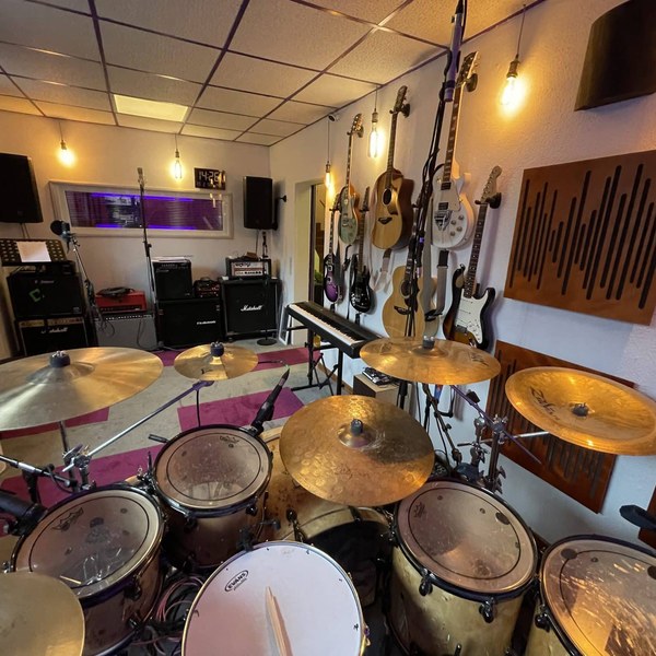 Foto von Aufnahmeraum 1 im StudioCarbon Tonstudio - Wiener Neudorf bei Mödling. Zu sehen sind ein mikrofoniertes Schlagzeug sowie einige Gitarren an Wandhalterungen